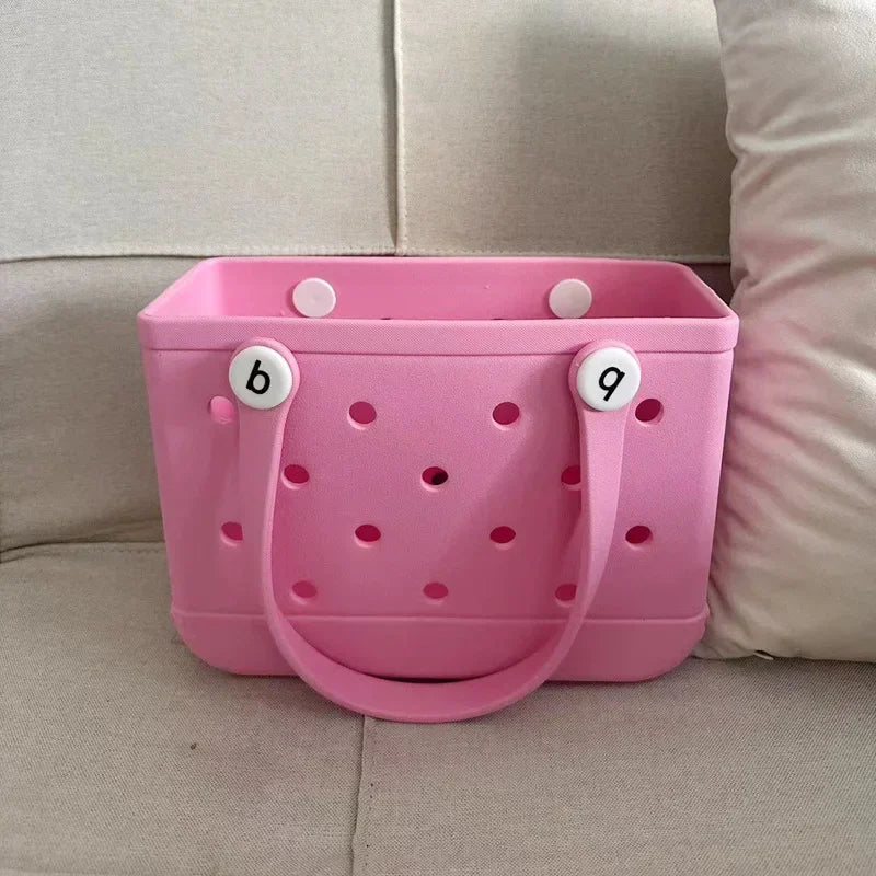 Pink storage basket with holes and handles on a beige couch